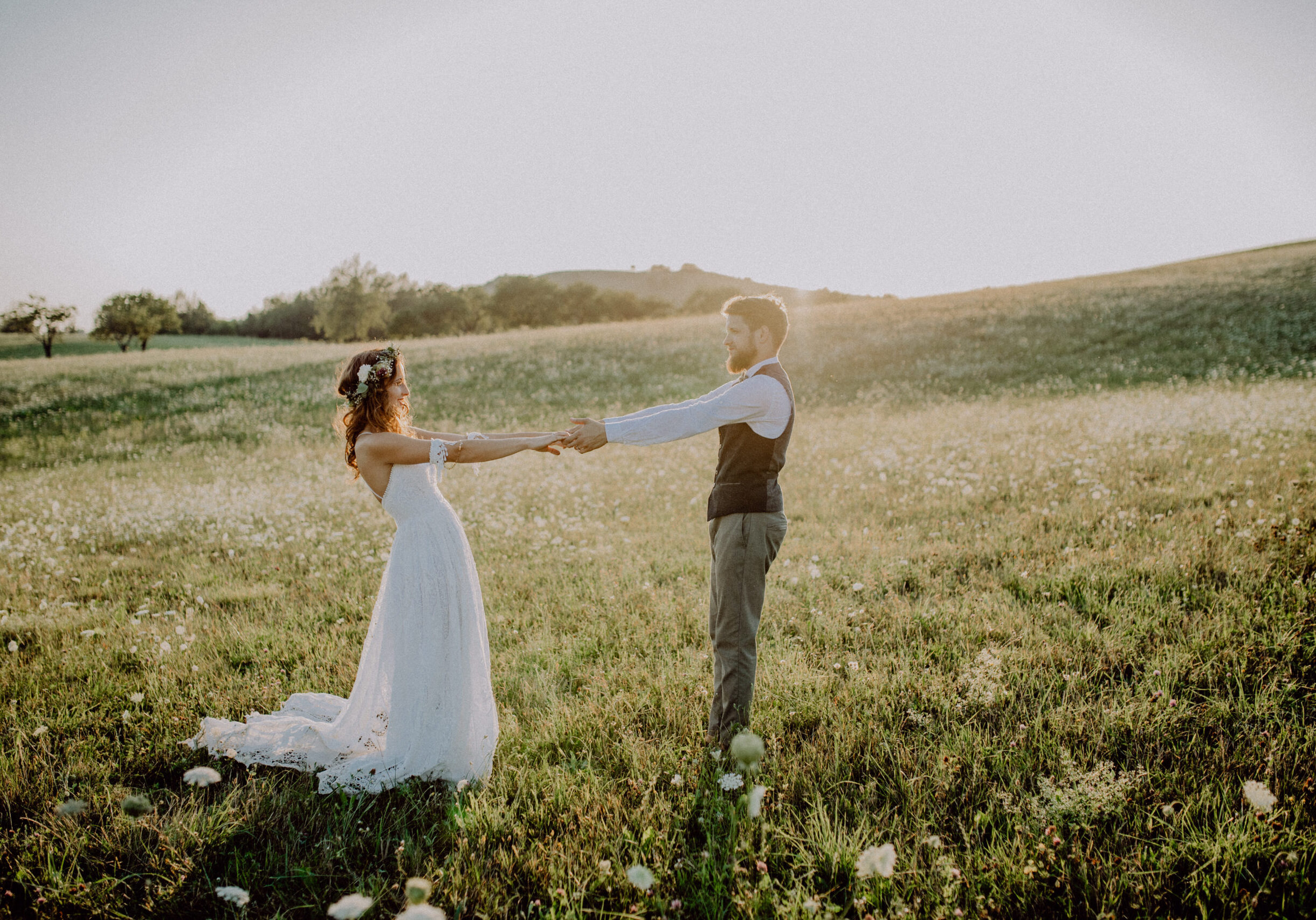 Beautiful young bride and groom outside in green nature at romantic sunset.