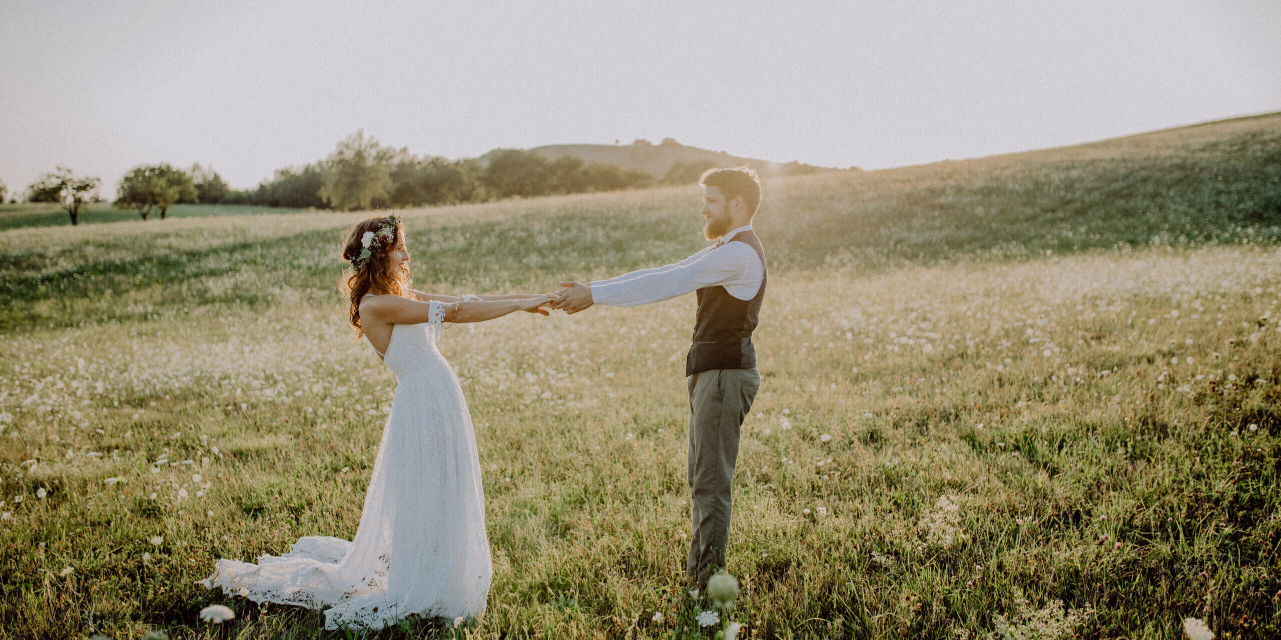 Beautiful young bride and groom outside in green nature at romantic sunset.