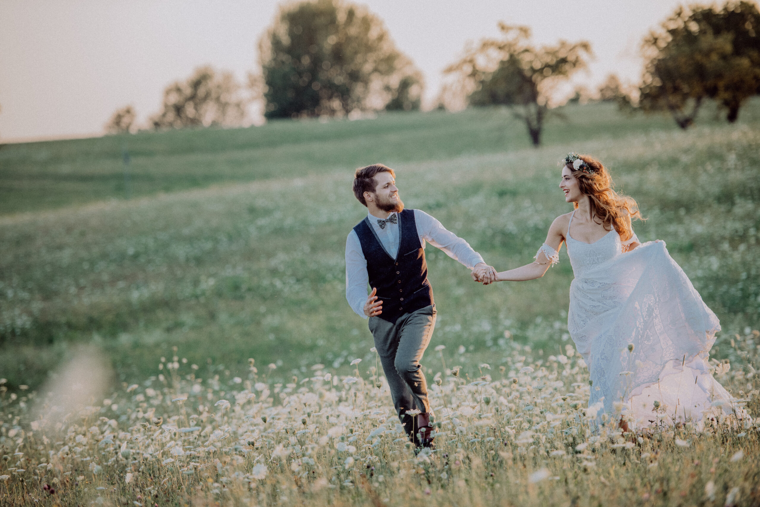 Beautiful young bride and groom outside in green nature at romantic sunset.